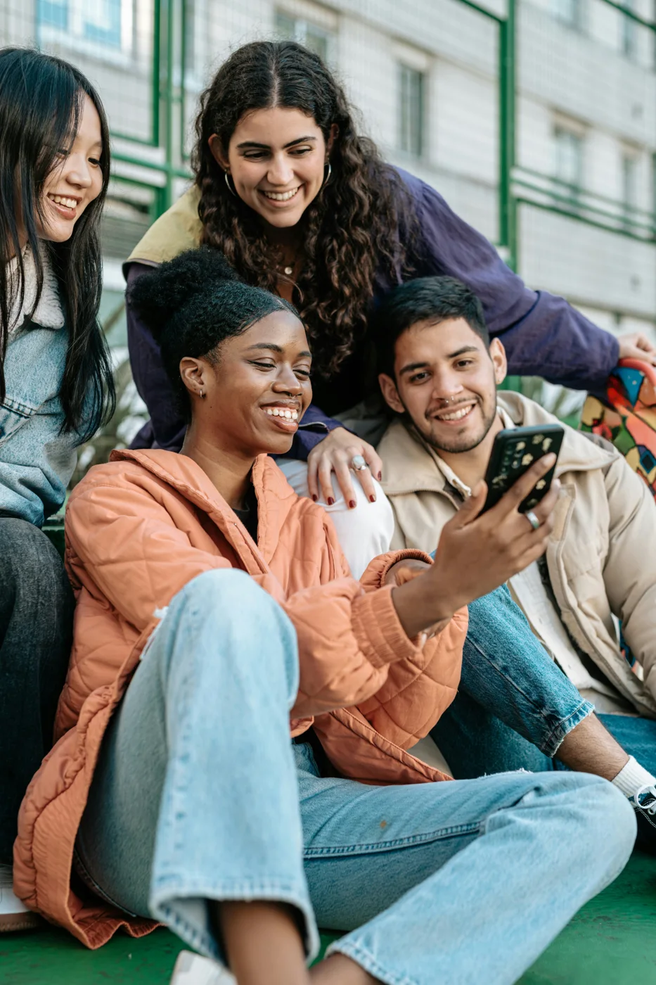 Cuatro amigos sonriendo mientras miran un teléfono