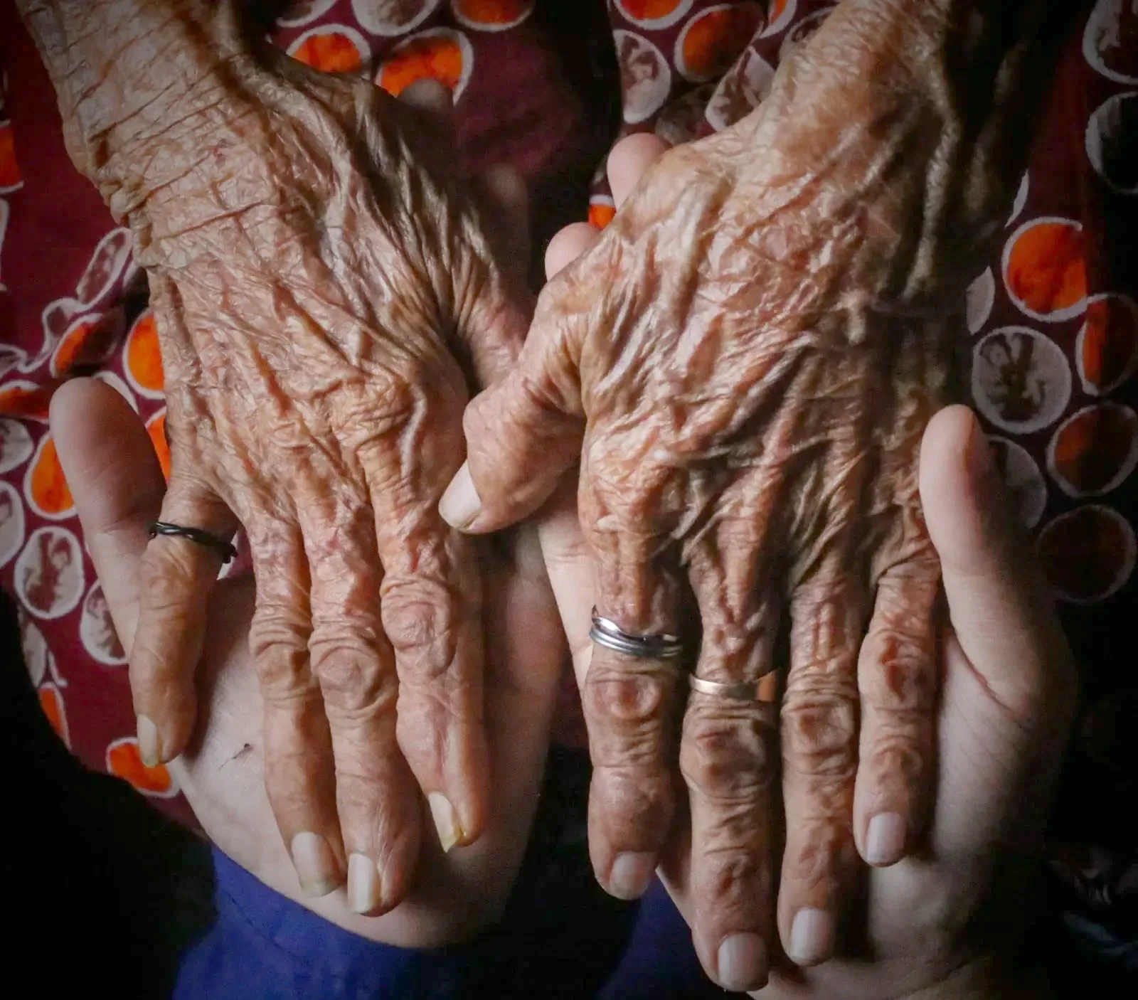 Las manos curtidas de una persona mayor descansando en las manos de alguien más joven
