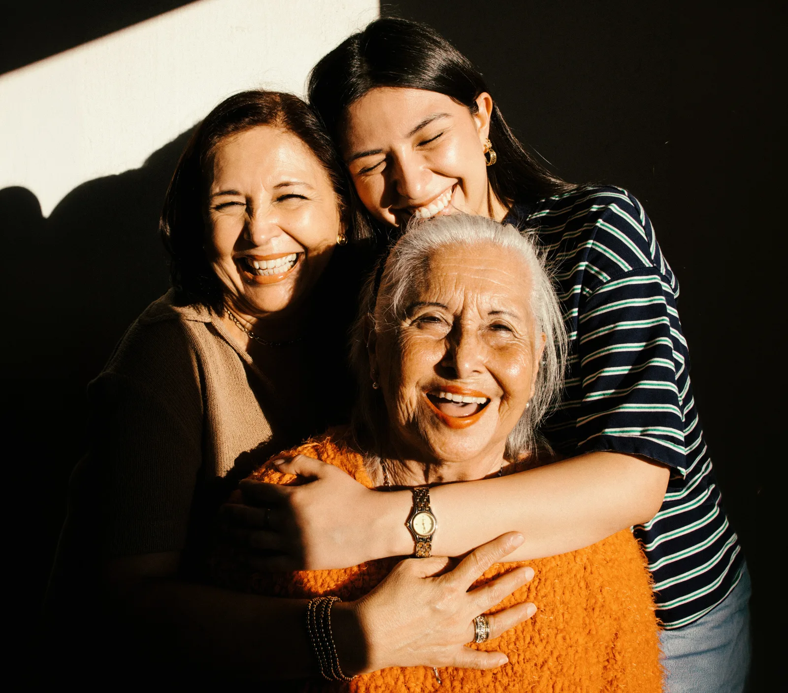Tres generaciones de mujeres abrazándose y riendo