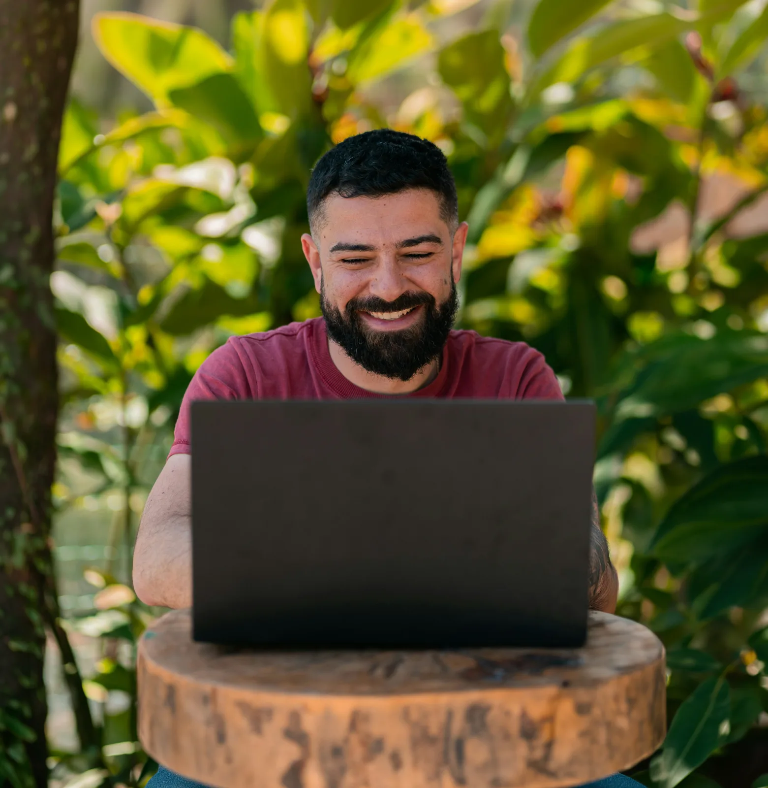 Un hombre sonriente usando una laptop al aire libre