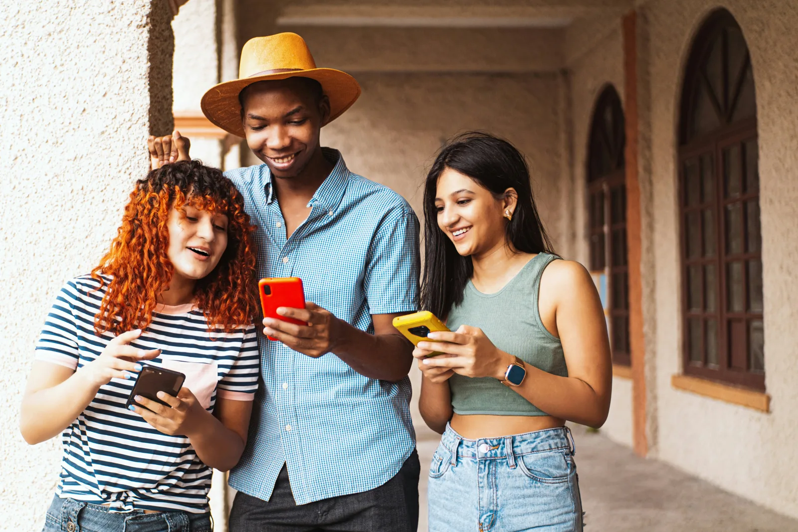 Tres amigos sonriendo mientras miran sus teléfonos
